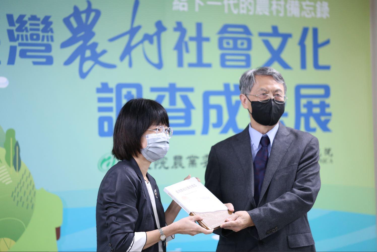 計畫總主持人王明珂院士（右）致贈研究成果《臺灣農村人類生態志．海豐村》予農委會企劃處副處長王玉真。